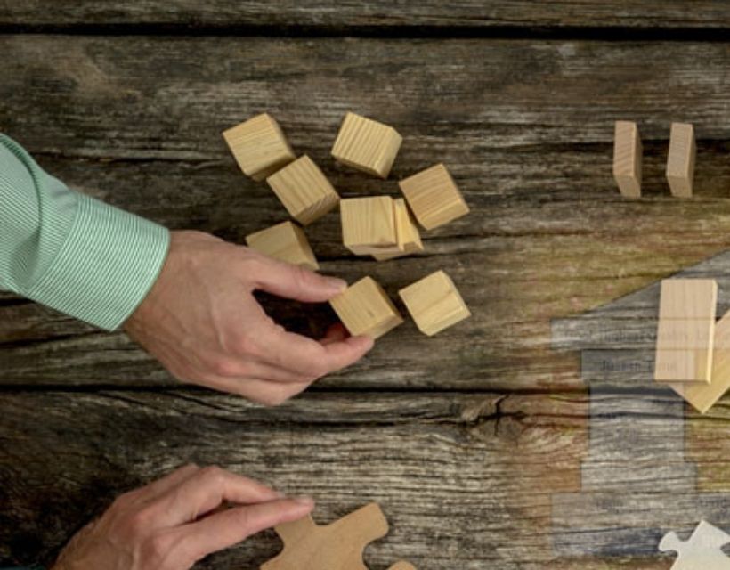 Hands moving blocks on a wooden table.