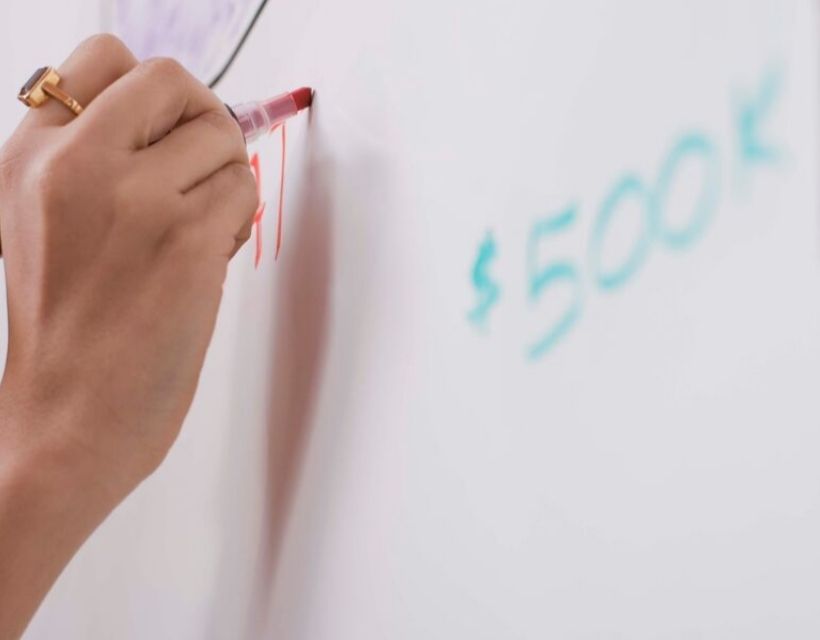 A woman's hand writing on a white board.